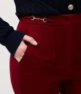 Pantalón flare de tiro alto confeccionado en tejido punto roma, con recortes frontales verticales que estilizan la silueta y detalle de hebilla metálica en la cintura.