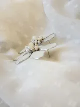 Par de aros colgantes con forma de flor blanca con borde plateado y centro de perlas y cuentas plateadas.