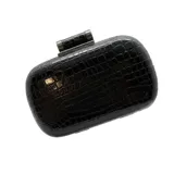 Cartera tipo clutch color negro con textura efecto cocodrilo y cierre metálico superior.