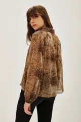 Camisa de manga larga con cuello camisero y cierre frontal de botones, confeccionada en tejido fluido con estampado animal print de leopardo.