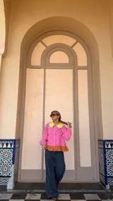 Camisa de manga larga en color rosa, con cuello Peter Pan en color amarillo y detalle de volados en los bordes. Presenta cierre frontal con botones y puños elásticos con detalle de volados.