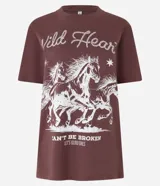 Remera de algodón color marrón, con cuello redondo, mangas cortas y estampado western de caballos con la frase 'Wild Heart' en color blanco.