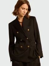 Blazer negro cruzado de lana virgen con solapas de muesca, cierre con doble botonadura con botones dorados, dos bolsillos con solapa en la parte delantera y puños con botones.