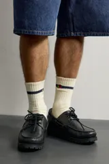 Zapato estilo náutico de piel color negro, de la colección especial Fruit of the Loom x Zara. Presenta detalle de bordón en el empeine, ojalillos metálicos dorados, cordones negros y suela track dentada.