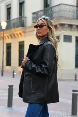 Blazer de cuero marrón con diseño recto y calce relajado. Cuenta con cierre frontal de un botón, solapas clásicas y bolsillos frontales parche.