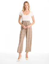 Enterito de diseño combinado con remera de cuello redondo y manga corta en color crema, integrada a un pantalón de corte recto y tiro alto con estampado a cuadros. Presenta cintura elastizada y bolsillos laterales inclinados.