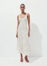 Vestido midi de viscosa fluida en color crudo con estampado de lunares negros, de corte recto, escote redondo, tirantes y bajo asimétrico.