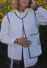 Chaleco acolchado de color blanco con diseño de rombos y bordes en color marrón oscuro. Presenta un bolsillo frontal con un detalle bordado de una rama con hojas en color marrón.