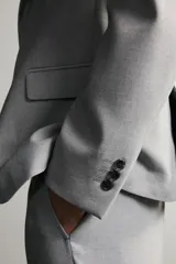 Pantalón de traje slim fit color gris, con bolsillos frontales, bolsillos traseros de doble vivo, trabillas para cinturón y cierre frontal con cremallera y botón.