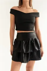 Pollera mini de seda fría con acabado tornasolado, diseño de tiro alto con faja en la cintura y falda con volados escalonados que aportan volumen.