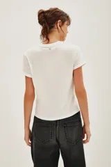 Remera blanca de algodón con cuello redondo y mangas cortas con dobladillo. Presenta un estampado sutil de pequeños corazones brillantes distribuidos por toda la prenda.