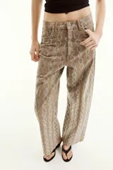 Pantalón de tiro medio en color marrón con diseño de animal print y aplicaciones de brillos en contraste. Cuenta con cinco bolsillos, presillas para cinturón y cierre frontal con cremallera y botón metálico.