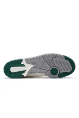 Championes New Balance modelo 550, de diseño retro inspirado en el básquetbol. Presenta una base de cuero blanco con detalles en verde oscuro y gris, incluyendo el logo 'N' con efecto desgastado y suela de goma con acabado envejecido.