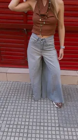 Pantalón de jean celeste de tiro medio con pierna extra ancha y caída fluida, con bolsillos delanteros y traseros, y cierre frontal con cremallera y botón metálico.