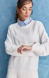 Sweater blanco de punto con diseño holgado, cuello redondo, mangas largas acampanadas y detalles de textura horizontal en el tejido.