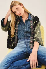 Kimono de estilo abierto con mangas amplias, confeccionado en viscosa con técnica de teñido tie-dye en tonos negro y verde oliva. Presenta una guarda frontal bordada con detalles de pedrería y apliques decorativos.