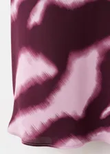 Vestido midi evasé con estampado animal print tipo cebra en tonos bordó y rosado, cuello redondo y manga larga.