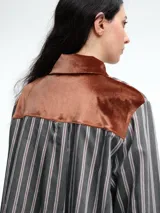 Camisa de corte relajado con estampado de rayas verticales, destacada por detalles en terciopelo en el cuello, puños y canesú. Presenta cierre frontal con botones y mangas largas.