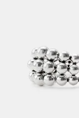 Pulsera rígida abierta con diseño de múltiples hileras de pequeñas esferas metálicas en acabado plateado envejecido.