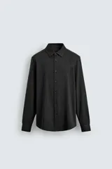 Camisa de corte relajado confeccionada en tejido de algodón con textura. Presenta cuello italiano, manga larga con puños abotonados y cierre frontal mediante botonadura.