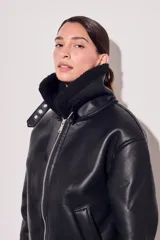 Campera negra de cuero sintético con cuello y puños de piel sintética. Corte oversize y cierre frontal con cremallera.