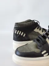 Zapatillas deportivas de caña alta con estampado de piel de reptil en tonos verde y negro, detalles en blanco y suela gruesa blanca.