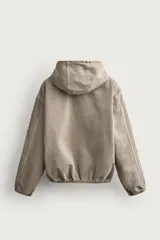 Cazadora de denim de algodón color negro con efecto lavado, de corte relaxed fit, manga larga y capucha. Cuenta con cierre frontal de cremallera, bolsillos frontales tipo canguro y acabados con elástico en puños y cintura.