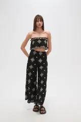 Top cropped negro, estilo strapless, con elástico en el busto y ruedo, y bordados blancos con motivos florales y geométricos.