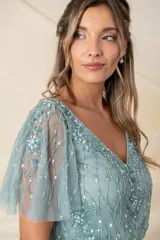 Vestido largo de tul bordado color verde agua, corte a la cintura y falda amplia. Las mangas son desmontables mediante broches, permitiendo usarlo sin mangas y combinarlo con un chal o túnica.