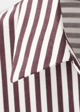 Camisa de corte recto confeccionada en mezcla de algodón y poliéster, con estampado de rayas. Cuenta con cuello camisero, manga larga con puños abotonados, bolsillo de parche en el pecho y cierre frontal con botones.
