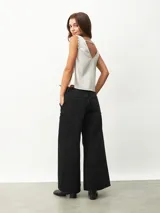 Blusa sin mangas color blanco off-white, con escote en V y detalles de encaje en los tirantes. Diseño holgado y fluido.