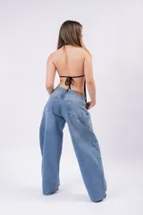 Blusa marrón con escote halter y diseño cruzado que genera un pronunciado escote en V y aberturas frontales. Confeccionada con tela ligera y drapeada, presenta un corte asimétrico con terminación en puntas colgantes.
