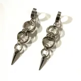 Par de aros colgantes plateados con cierre de clip, formados por eslabones circulares unidos entre sí y un dije en forma de pincho.