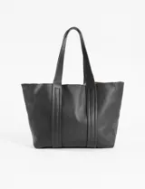 Cartera tipo shopper de cuero vegano color negro con textura granulada, doble asa de hombro fija y detalles de pespuntes verticales en el frente.