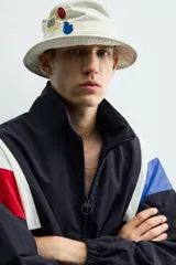 Chaqueta técnica de corte relajado con cuello subido y cierre frontal de cremallera bidireccional. Presenta un diseño color block en tonos azul marino, blanco, rojo y azul eléctrico. Incluye bolsillos frontales de vivo, puños y ruedo elásticos, y forro interior de red.