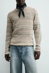 Camiseta de manga larga con cuello redondo y ajuste relajado, confeccionada en tejido de punto con estructura abierta y patrón de rayas horizontales.