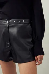 Short negro de cuero sintético con cintura con tachas metálicas.