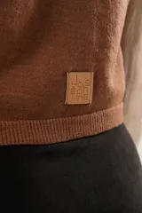 Chaleco color café de tejido sintético con escote en V y cierre frontal con botones forrados.