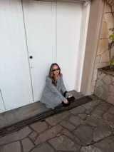 Conjunto de dos piezas compuesto por un blazer y un pantalón de corte sastrero, confeccionados en tela de algodón con estampado de rayas verticales blancas sobre fondo gris. El blazer presenta solapas clásicas y cierre frontal, mientras que el pantalón es de tiro medio y pierna recta.