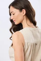 Musculosa de lino color beige, con cuello mao y escote en V, cierre frontal con botones y dos bolsillos plaqué con solapa en el pecho.