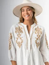 Vestido corto blanco de algodón italiano con bordado azul, mangas tres cuartos y botones frontales. Tiene forro interior en la falda.