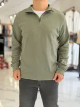 Buzo de algodón color verde militar con cuello alto y cierre frontal parcial tipo medio cierre, manga larga y puños de rib elástico.