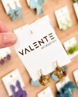 Par de aros colgantes con aro dorado y dije de acrílico transparente color caramelo con forma de flor. El aro es de acero y la flor de acrílico.