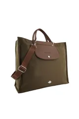 Cartera tipo tote de diseño amplio en color beige, con solapa superior y asas en color marrón. Incluye una correa larga regulable y desmontable con logo grabado, y un aplique metálico en forma de labios en la parte inferior.