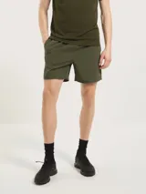 Bermuda deportiva de corte recto y largo medio, confeccionada en tejido técnico ligero de color verde oliva. Cuenta con cintura elástica y bolsillos laterales.