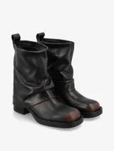 Bota de cuero color negro, de caña media con diseño arrugado y taco bajo.