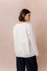 Buzo de calce relajado color beige, con cuello redondo, manga larga y recortes curvos decorativos con costuras a la vista en el frente. Terminaciones en puños y cintura.