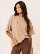 Remera oversize color tostado, con mangas cortas y cuello redondo. Presenta un gran estampado en la espalda con la inscripción "Morning Person Society" y un texto secundario en tipografía más pequeña.