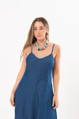 Vestido largo de denim fino y liviano, color azul, con breteles finos, escote en V y falda amplia con recortes verticales y bolsillos laterales.