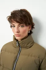 Campera puffer corta color beige de nylon, con cuello alto, cierre frontal y bolsillos laterales con cierre.